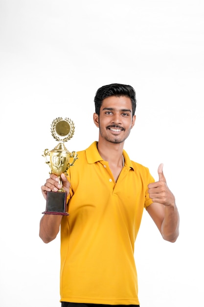Jeune homme indien tenant un trophée et faisant le geste du gagnant