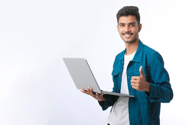 Jeune homme indien utilisant un ordinateur portable et montrant des coups sur fond blanc.