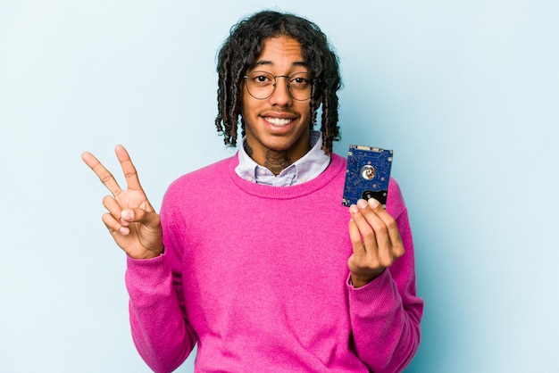 Jeune homme informatique afro-américain isolé sur fond bleu joyeux et insouciant montrant un symbole de paix avec les doigts