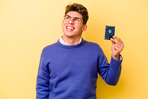 Jeune homme d'informatique caucasien isolé sur fond jaune rêvant d'atteindre des objectifs et des buts