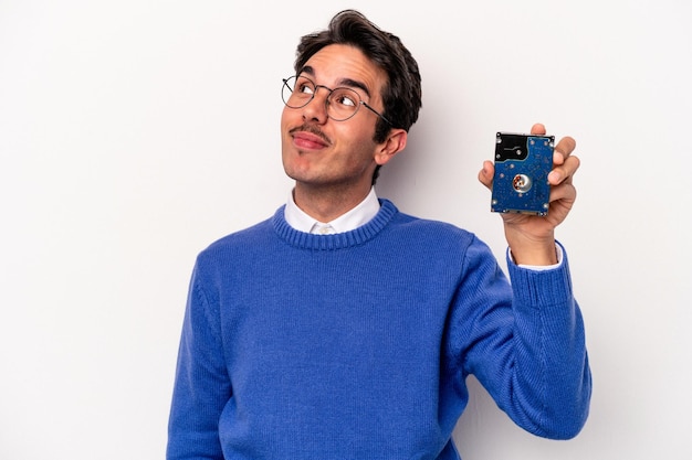 Jeune homme informatique caucasien tenant un disque dur isolé sur fond blanc rêvant d'atteindre des objectifs et des buts