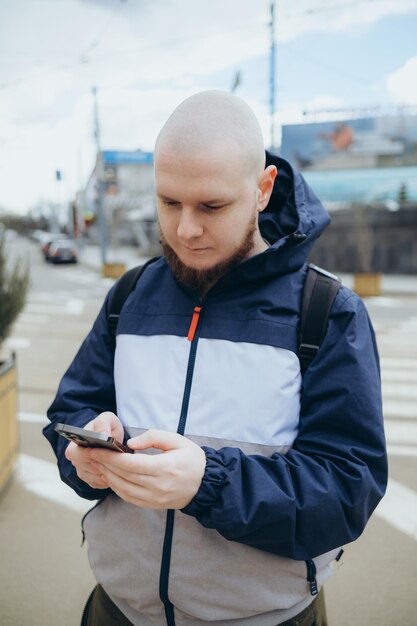 Jeune homme irlandais souriant heureux à l'aide de smartphone à la ville