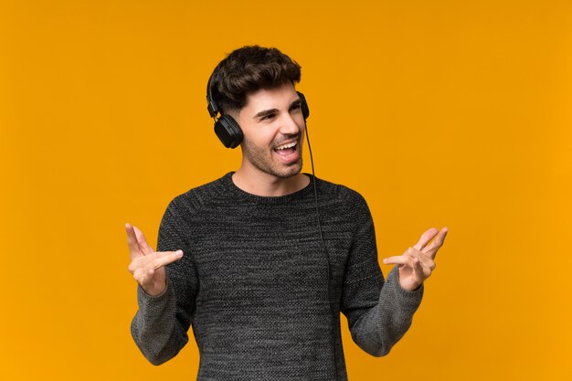 Jeune homme sur isolé à l'aide du mobile avec casque et danse