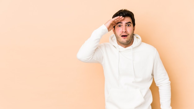 Jeune homme isolé sur un espace beige crie fort, garde les yeux ouverts et les mains tendues.