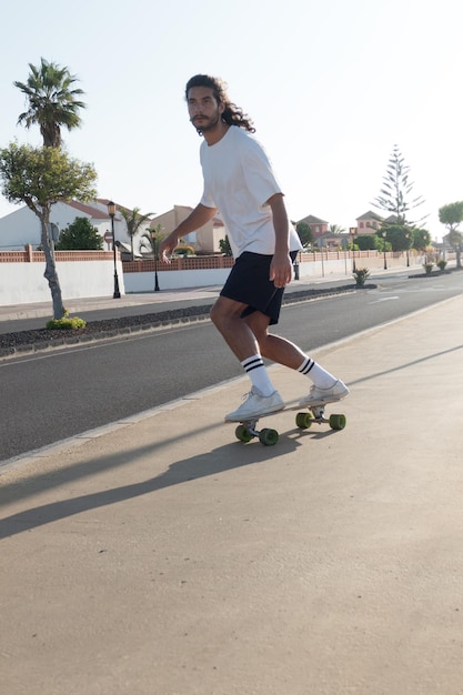 Jeune homme italien caucasien patinant sur son surfskate à l'extérieur dans une journée d'été ensoleillée