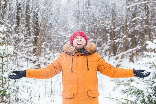 Jeune homme jetant de la neige dans la forêt d'hiver. Guy s'amuser à l'extérieur. Activités hivernales.