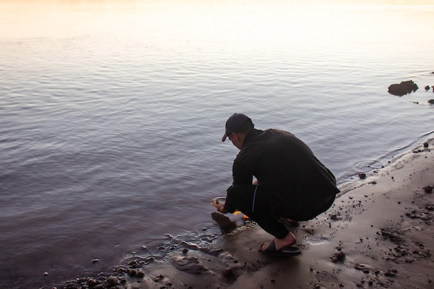 Jeune homme jetant un poisson dans l'eau au bord de la rivière.