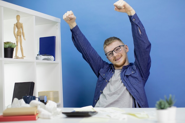 Photo jeune homme jette volontiers ses mains sur la calculatrice du budget national et les reçus