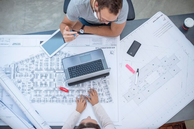 Un jeune homme et une jeune femme discutent d'un projet dans un bureau de conception.