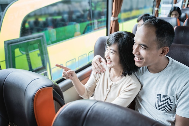 Un jeune homme et une jeune femme du doigt pointant vers la fenêtre alors qu'il était assis sur le bus lors d'un voyage