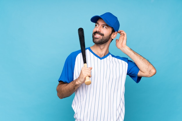 Jeune homme jouant au baseball sur bleu isolé, pensant une idée