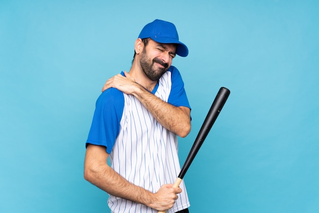 Jeune homme jouant au baseball sur bleu souffrant de douleur à l'épaule pour avoir fait un effort