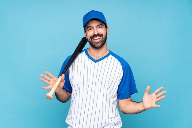 Jeune homme jouant au baseball sur fond bleu isolé souriant