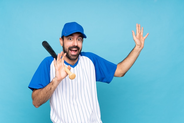 Jeune homme jouant au baseball sur un mur bleu isolé nerveux et effrayé