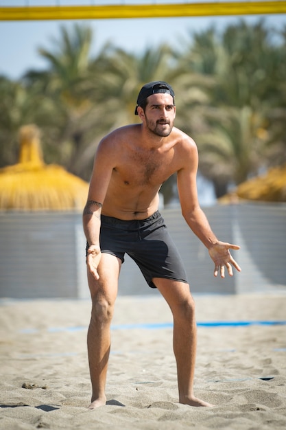 Photo jeune homme jouant au beach-volley sur la plage par une journée ensoleillée