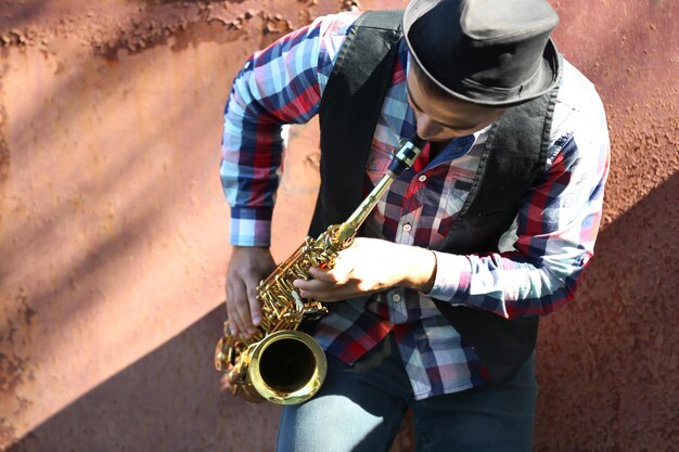 Jeune homme jouant au saxophone à l'extérieur près de l'ancien mur