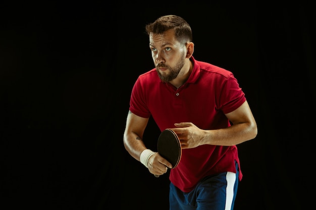 Jeune homme jouant au tennis de table sur fond noir