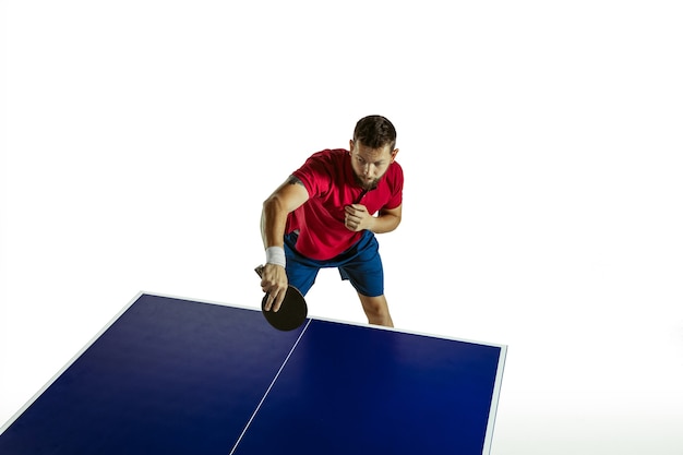 Jeune homme jouant au tennis de table sur mur blanc