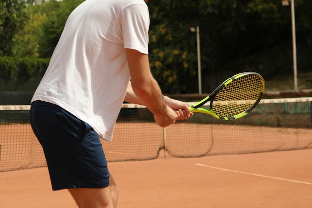 Jeune homme jouant au tennis sur terre battue