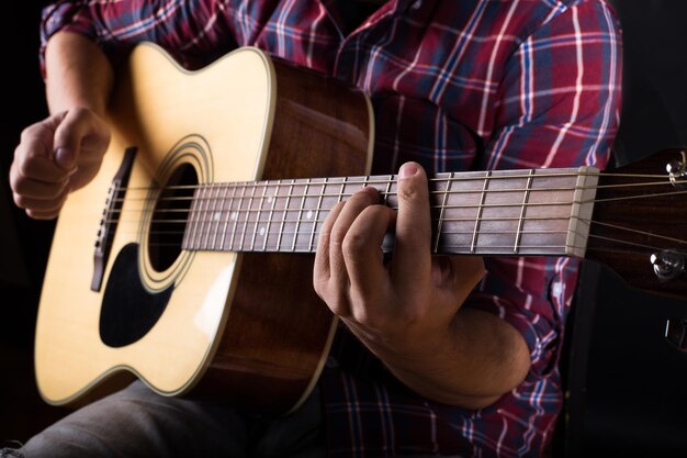 Jeune homme jouant de la guitare acoustique en studio