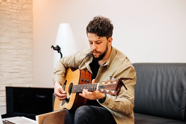 Jeune homme jouant de la guitare sur le canapé