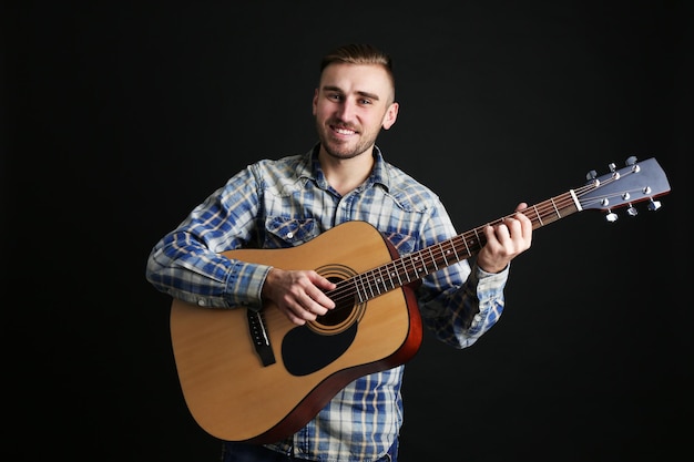 Jeune homme jouant de la guitare sur fond sombre