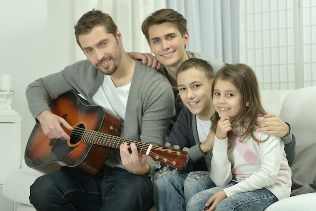 Jeune homme jouant de la guitare pour sa famille