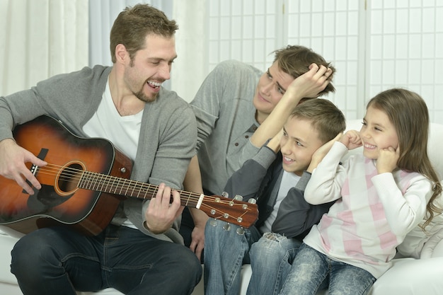 Jeune homme jouant de la guitare pour sa famille