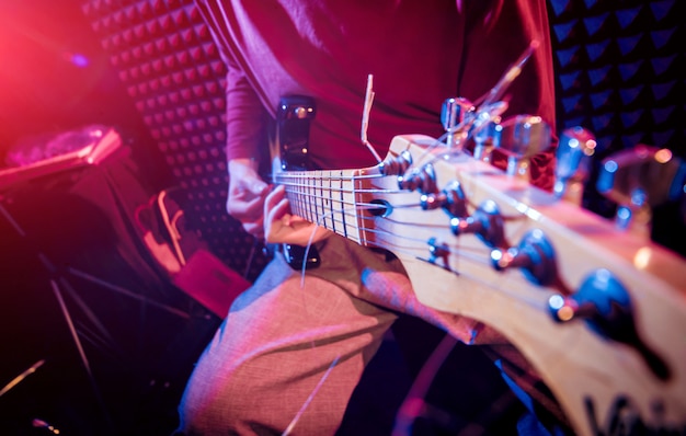 Jeune homme jouant de la guitare en studio d'enregistrement sonore.