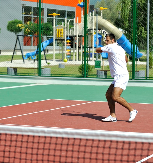 Photo un jeune homme joue au tennis à l'extérieur.