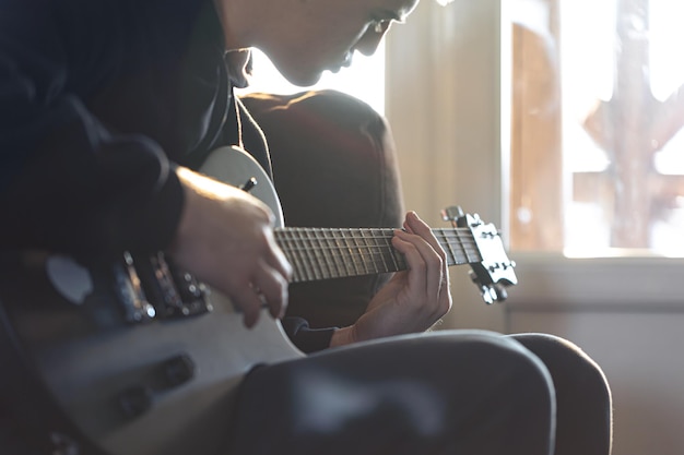 Un jeune homme joue de la guitare électrique dans sa chambre