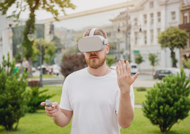 Un jeune homme joue à un jeu avec des lunettes de réalité virtuelle dans la rue.