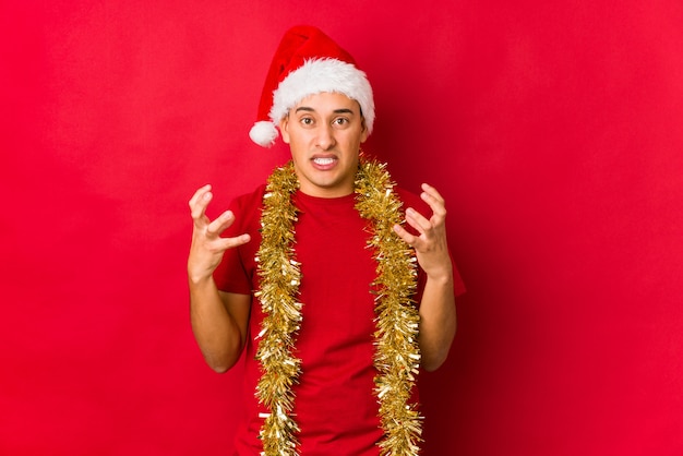 Jeune homme le jour de Noël en colère crier avec les mains tendues.