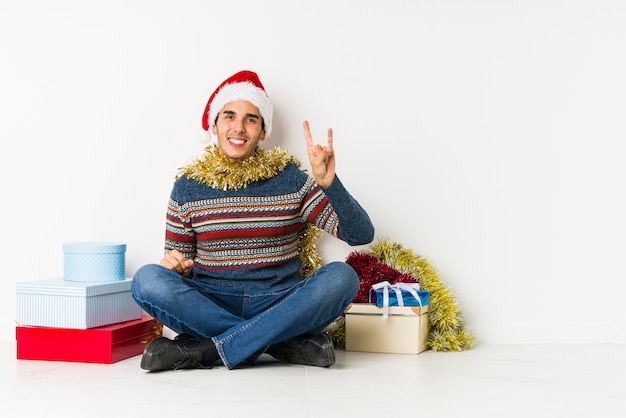 Jeune homme le jour de Noël en criant et en tenant la paume près de la bouche ouverte.