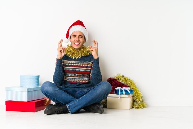 Jeune homme le jour de Noël debout avec la main tendue montrant le panneau d'arrêt, vous empêchant.