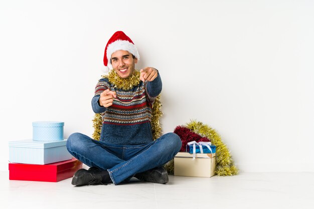 Jeune homme, le jour de Noël, fronçant le visage avec mécontentement, garde les bras croisés.