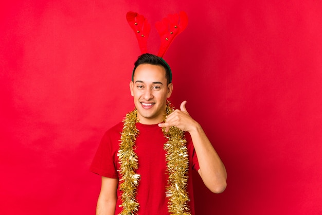 Jeune homme le jour de Noël montrant un geste d'appel avec les doigts.