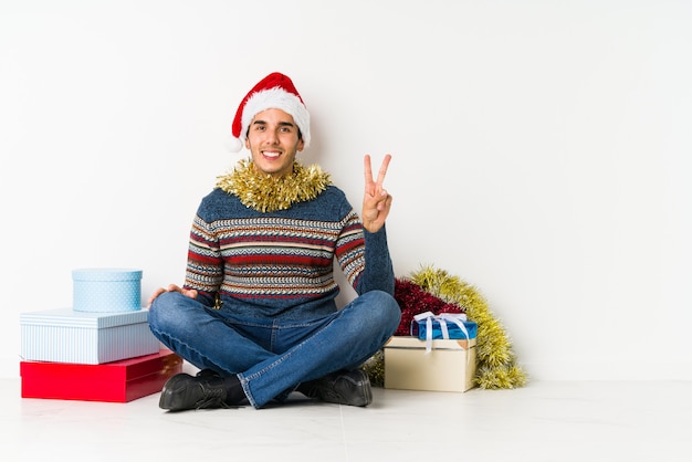 Jeune homme le jour de Noël, montrant le numéro un avec le doigt.