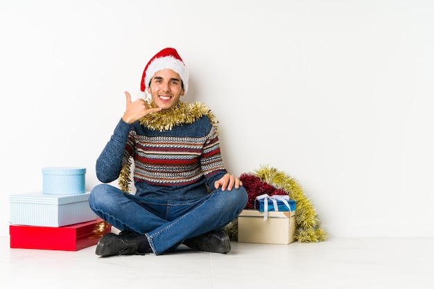 Jeune homme le jour de Noël montrant les pouces vers le haut et vers le bas, difficile choisir le concept