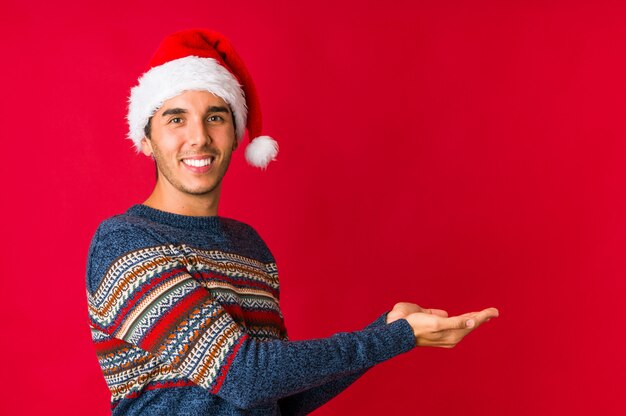 Jeune homme le jour de Noël semble de côté souriant, gai et agréable.