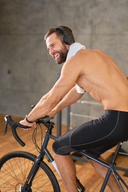 Jeune homme joyeux écoutant de la musique et faisant du vélo de papeterie