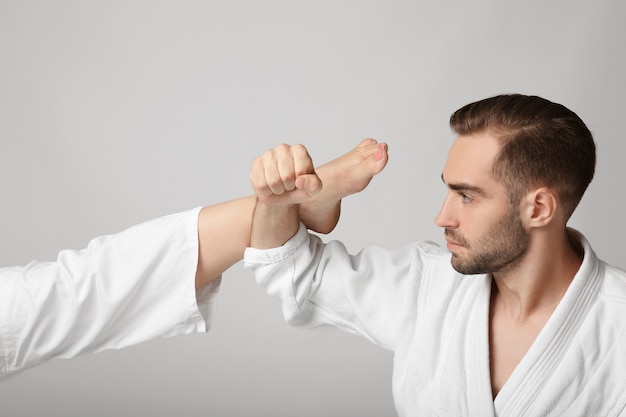 Jeune homme en karategi coup de pied de blocage sur une surface légère