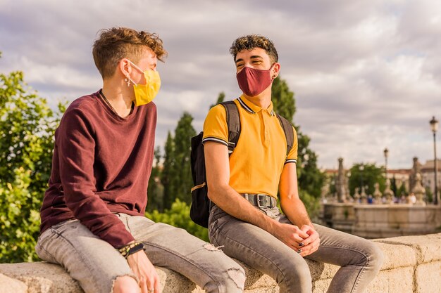 Jeune homme latin et amis transgenres hispaniques pendant le nouveau masque facial normal à distance sociale