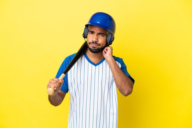 Jeune homme latin colombien jouant au baseball isolé sur fond jaune ayant des doutes