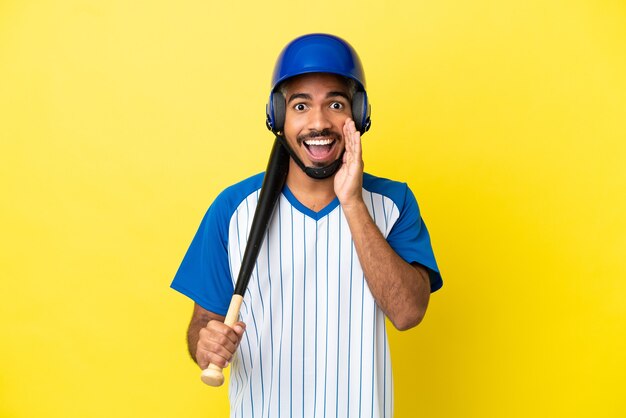 Jeune homme latin colombien jouant au baseball isolé sur fond jaune avec une expression faciale surprise et choquée