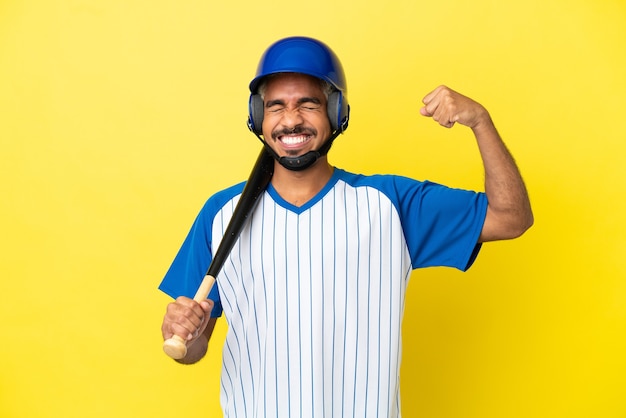 Jeune homme latin colombien jouant au baseball isolé sur fond jaune faisant un geste fort
