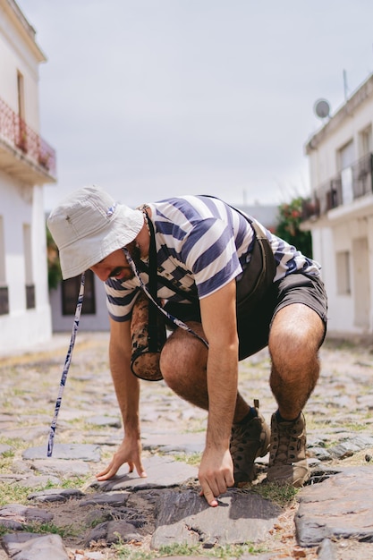 Jeune homme latin essayant de se lever du sol dans une rue pavée Photo verticale