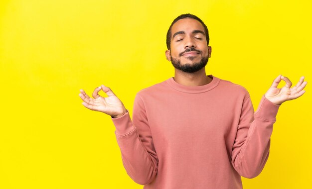 Jeune homme latin isolé sur fond jaune dans une pose zen