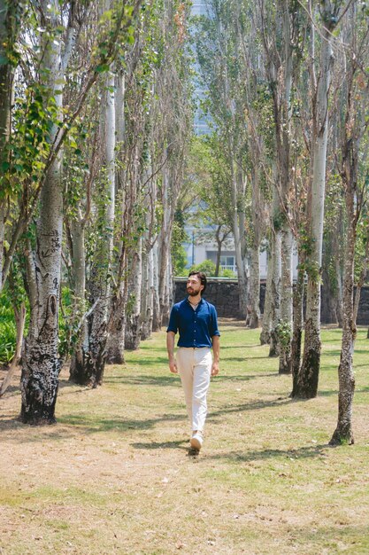 Jeune homme latin marchant à travers des arbres ombragés élégant trouvant son espace de copie de soi intérieur