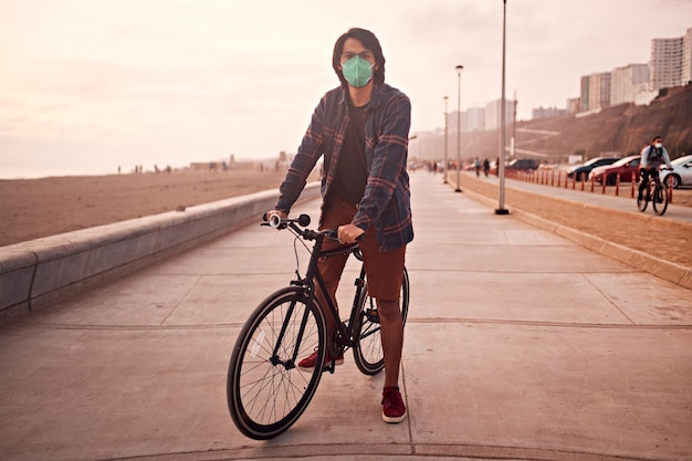 Photo le jeune homme latin monte une bicyclette pendant un beau coucher du soleil